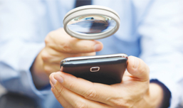 man using magnifying glass on mobile phone